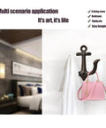 Badass Vintage Cast Iron Nautical Anchor Wall Hooks For Bathrooms And Closets holding a white towel and pink bag.