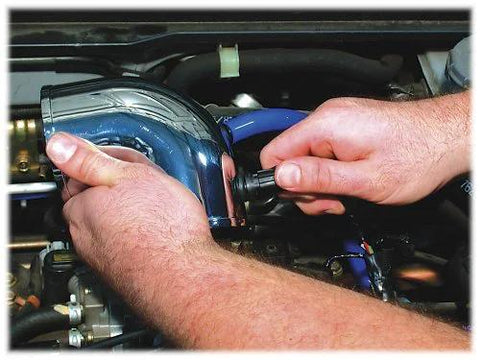 Spectre Performance 8711 vacuum sensor adapter kit, blue aluminum connector being installed in engine bay.