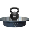 Electric Motorized Rotating Display Stand With 360 Degree Turntable For Product Photography Jewelry Cake And 3D Models That Spins Smoothly Shows Everything From Every Angle Like A Boss At Work with an 8kg kettlebell on a reflective surface.