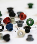 Assorted precision machined chainring bolts and nuts for 1x drivetrains, including 4 mm hex bolt and 6 mm hex nut, on a blueprint.