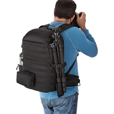 Person carrying an All Weather Camera Backpack With Padded 15.6 Inch Laptop Compartment, tripod attached, outdoor setting