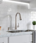 Barulli Kitchen Faucet With Pull Down Sprayer And Soap Dispenser, Single Handle, High Arc, Spot Defense Stainless Steel Finish, Easy Dock MagnePfit System for busy kitchens shown on a marble countertop with white tile backsplash.