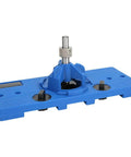 Front view of blue plastic cabinet hinge drilling guide jig with central metal guide post.