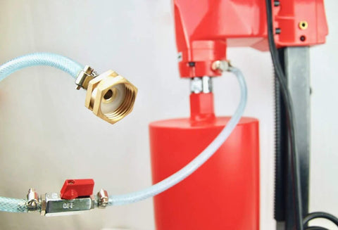 Close-up view of brass hose adapter with blue braided hose on a red core drill unit