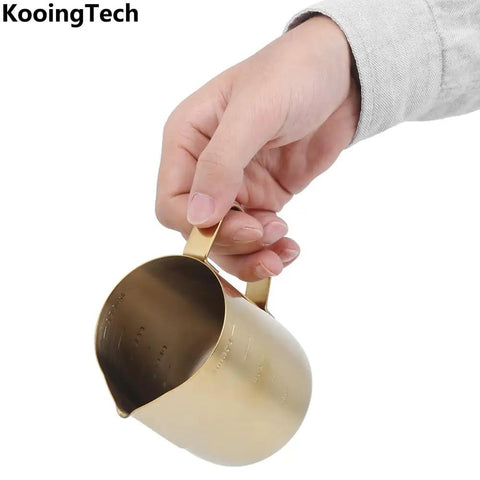 Person holding Gold 350Ml Stainless Steel Milk Frothing Cup With Clear Scale For Home Or Office Use Barista Grade Milk Frother Pitcher