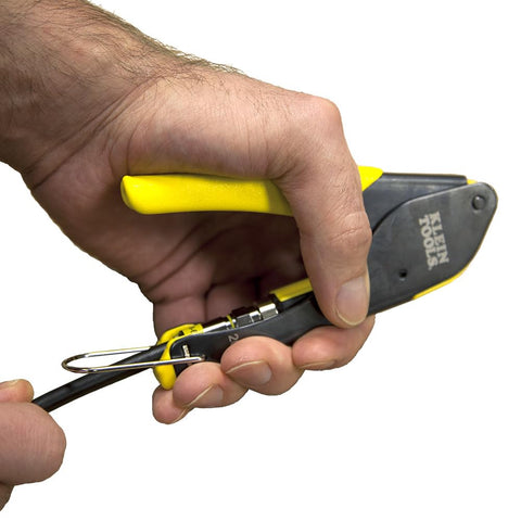 Close-up of hand using Coax Installation Kit With Crimp Tool, Cable Cutter, Stripper and F Connectors on black coax cable.