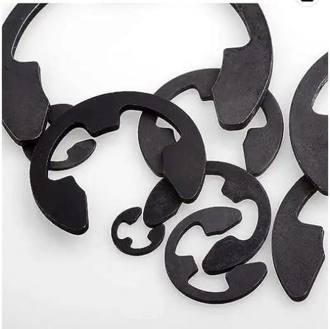 Close-up of Durable Spring Steel E Clips With Black Oxide Finish One Eighth Inch Ten Pack Retaining Clips For Auto And Machinery Gearhead DIY Projects Rust Resistant Easy Install High Strength Clips scattered.