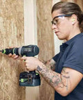 Person using Badass Cordless Drill Driver Featuring Ec Tec Brushless Motor on wooden panel for heavy-duty tasks.