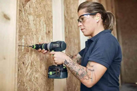 Person using Badass Cordless Drill Driver Featuring Ec Tec Brushless Motor on wooden panel for heavy-duty tasks.