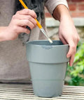 Person applying epoxy repair putty stick 2 oz hand mixable two part system all purpose quick set adhesive on grey pot outdoors
