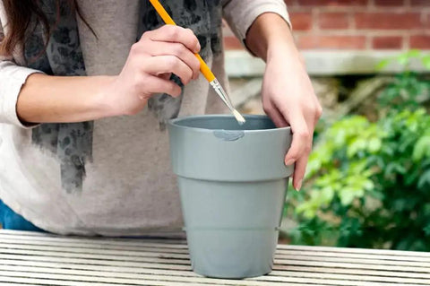 Person applying epoxy repair putty stick 2 oz hand mixable two part system all purpose quick set adhesive on grey pot outdoors
