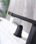 Close-up of 8 inch widespread bathroom faucet with two handles, pop up drain, water supply lines, matte black finish, in use