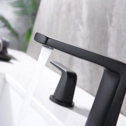 Close-up of 8 inch widespread bathroom faucet with two handles, pop up drain, water supply lines, matte black finish, in use