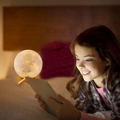 Girl in a cozy bedroom reading near a Lit Moon Lamp 3D Printed LED Night Light With 16 Color RGB Modes Remote And Touch Control Adjustable Brightness USB Recharge Realistic 6 Inch Moon Decor For Kids And Birthday Gift.