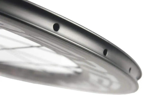Close-up of 700C Carbon Wheelset Aero Beast clincher rim edge showing holes, Toray T700 fiber material for road bikes.