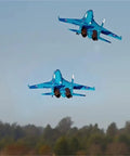 Two blue 6 Channel RC Plane SU 27 70mm Ducted Fan EDF jets in flight over a landscape, demonstrating realistic aerobatic maneuvers.