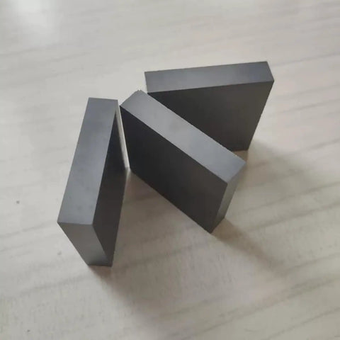Three hardwearing boron carbide ceramic square sheets 10mm by 50mm by 50mm shown on a surface for scientific research insulating plate use.