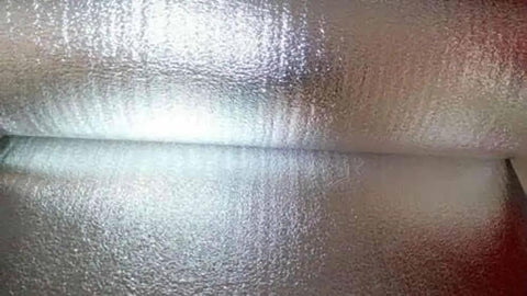 Double Sided Reflective Foam Insulation Roll That Blows Away Utility Bills Blocks Radiant Heat Quick Peel Hang For Attics Walls And Crawlspaces R8 Rated Ultra Thick Five Millimeter Core Seventy Two By Two Hundred Feet Made In Usa showcasing shiny, reflective surface of the insulation roll.