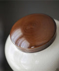 Top Tier Ceramic Loose Tea Storage Jar With Secure Lid featuring a smooth brown wooden lid for kitchen organization.