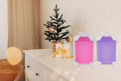 Lijinhe mini suitcase favor boxes with wheels, pink and purple, two shown on a white table beside a Christmas tree