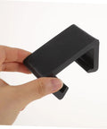 Hand holding a black clip from the 12 Piece Outdoor Furniture Clips For Sofa And Patio Wicker Chairs Easy To Install No Tools Needed Sturdy Rattan Connectors For Securing Couches Cushions And Sectionals On Patio Sets