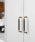 Installed 6 Pack 5 Inch Antique Brass Knurled Cabinet Pull Handles with textured non slip grip on white kitchen cabinet doors.
