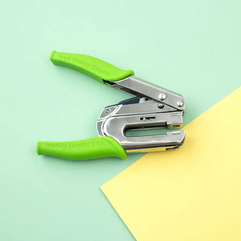 Crop-A-Dile Power Punch For One Quarter Inch Holes Scrapbooking Tool on paper, showing green handles and metal punch.