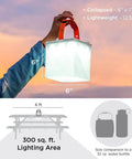 Person holding 2 In 1 Solar Camping Lantern and Phone Charger with 300 Lumens of Bright LED Light, Red Night Mode, outdoors at sunset.