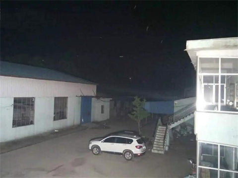 Heavy Duty Rechargeable Floodlight IP66 Waterproof High Power LED Work Light illuminating a dark industrial area with a white car.