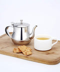 Mini 360Ml Stainless Steel Teapot For Tea And More on wooden tray, with cup of tea and crackers