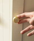 Close-up of hand installing a 2 Pack Brushed Gold Cabinet Knobs Set Vintage Retro Drawer Pulls For Kitchen Cabinets Cupboard Bathroom Dresser Zinc Alloy Hardware Handles Durable Easy Install Old School Charm on a cabinet door.