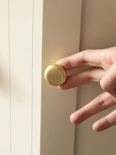 Close-up of hand installing a 2 Pack Brushed Gold Cabinet Knobs Set Vintage Retro Drawer Pulls For Kitchen Cabinets Cupboard Bathroom Dresser Zinc Alloy Hardware Handles Durable Easy Install Old School Charm on a cabinet door.