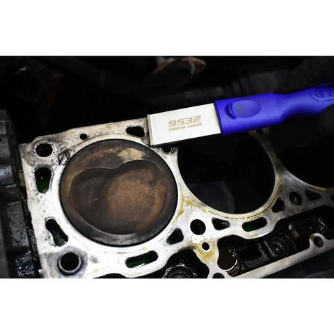 Close-up of Tungsten Carbide Gasket Scraper With Rectangular 90 Degree Blade in use on engine block surface, white finish.