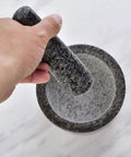 Person using Marble Mortar And Pestle Set With Brass Base For Guacamole Herbs Garlic And Spices Large Stone Grinder