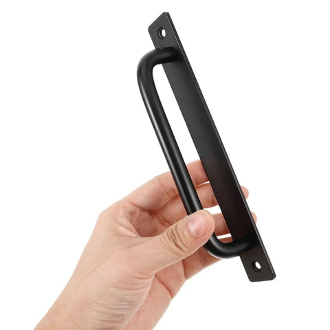 Hand holding black aluminum barn door handle from set of 4 surface mounted sliding cabinet door pulls built to last heavy duty alloy