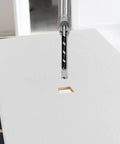 These Kickass Woodworking Drill Bits Feature Two Top Notch Square Hole Chisels For Fast Hollow Mortising On Any Lumber Project Including Half And Five Sixteenths Inch Sizes Today with drill bit in action creating square hole on white surface.