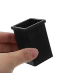 Black plastic TEHAUX square-tube connector sleeve for 1.57 x 2.36 in square tubing, held in hand