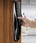Heavy Duty Smart Door Lock Featuring Biometric Fingerprint Scanner App Control Passcode Entry Built In Theft Alarm And Long Lasting Battery For Dead Simple Home Protection Setup installed on wooden door with hand entering passcode.