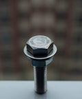Close-up of a stainless steel flat washer under a hex bolt head on a white surface.