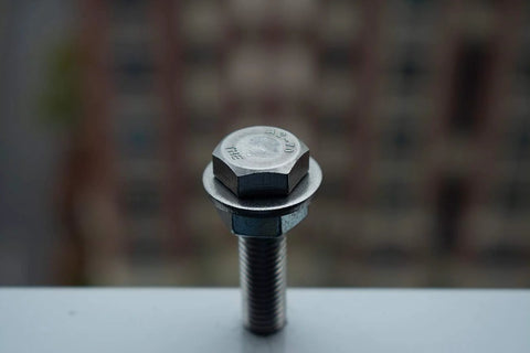 Close-up of a stainless steel flat washer under a hex bolt head on a white surface.