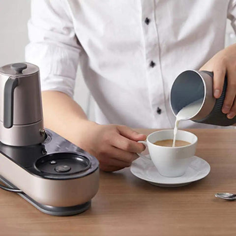 Mini Espresso Maker With Dual Pressure Extraction And Silky Milk Frother Styled Like A Classic Moka Pot One Touch Timer pouring frothed milk into a cup.