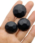 Three matte black upholstery tacks displayed on a hand, part of a Sixty Piece Bundle Of Hella Sturdy Matte Black Upholstery Tacks.
