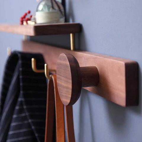 Wall Mounted Coat Rack Featuring Dope Top Shelf For Keys And Jackets Solid Hardwood Construction Plus Durable Brass Hooks Hella Sturdy Design Effortless Entryway Makeover Totally Sleek Modern Finish close-up shows hooks and shelf with belts hanging.