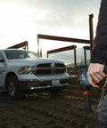 Worker holding 18V Brushless Dual Mode Impact Driver And Wrench With 1800 In Lbs Torque and 4200 IPM near construction site with truck