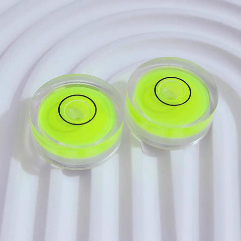 Four Pack Tiny Circular Bubble Levels With Double Sided Adhesive Backing Stick On Spirit Level Gauges For Quick Layouts And Precise Leveling On Cabinets Walls Tile And DIY Projects On The Go. 25mm neon acrylic circular levels on white surface