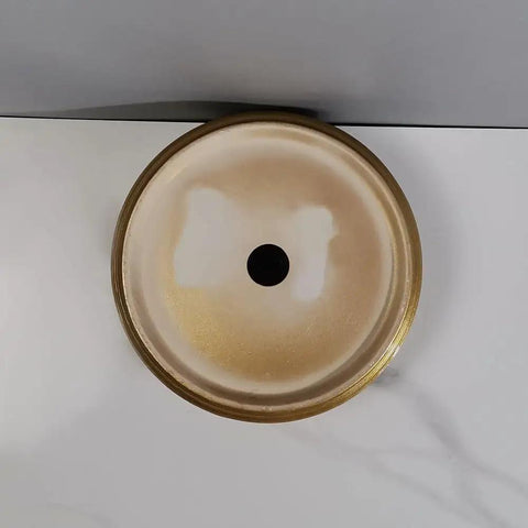 Top view of round golden bathroom sink vessel, showing shiny finish and black drain hole, elegant for modern bathrooms.