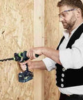 Person using a Heavy Duty Cordless Percussion Drill With Real Deal Masonry Punching Power And Smooth Woodworking Flow Including Forstner Bit Compatibility Plus No Nonsense Workhorse Design Tool Only on an OSB wall.