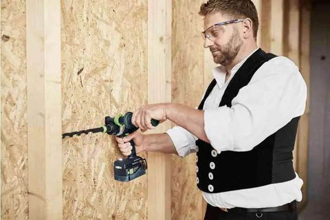 Person using a Heavy Duty Cordless Percussion Drill With Real Deal Masonry Punching Power And Smooth Woodworking Flow Including Forstner Bit Compatibility Plus No Nonsense Workhorse Design Tool Only on an OSB wall.
