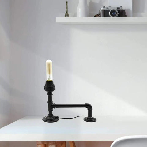 Industrial-style table lamp made with a malleable iron pipe fitting showcasing DIY design with vintage decor feel on a white desk.