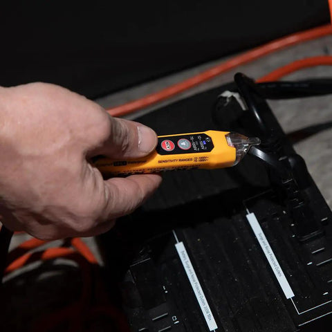 Hand using Dual Range Non Contact Voltage Tester 12 To 1000V AC Pen With Flashlight Audible Alarm And LED Indicator in a dark area